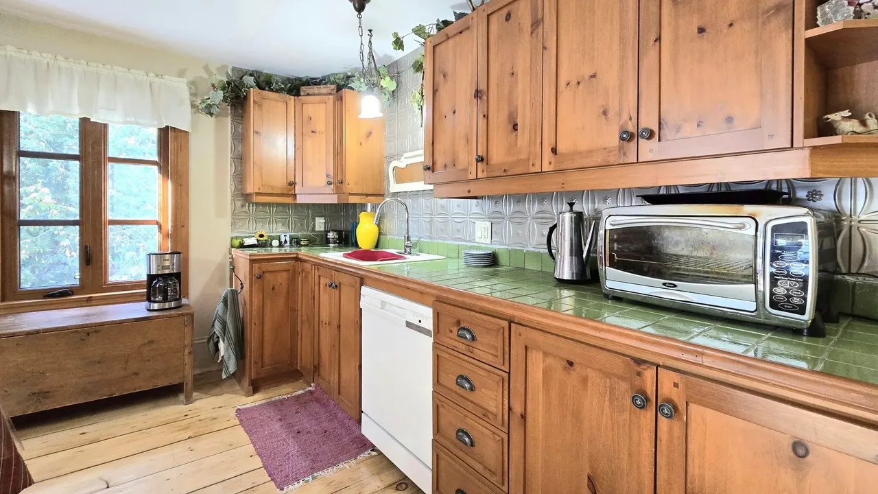 La cuisine du logement principal, ses armoires de bois et son comptoir vert