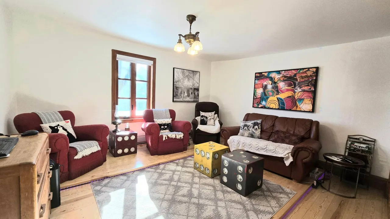 Le salon du logement principal, ses fauteuils et son plancher de bois